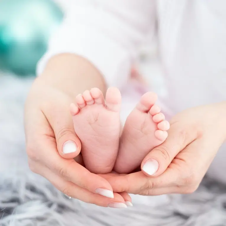 une femme tient les pieds d'un bébé dans ses mains