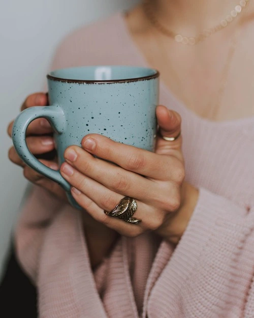 deux mains tiennent un mug bleu de thé bleu