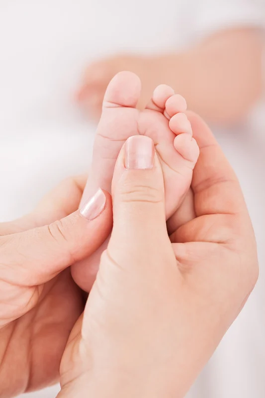 Un pied de bébé en train de se faire masser par un réflexologue