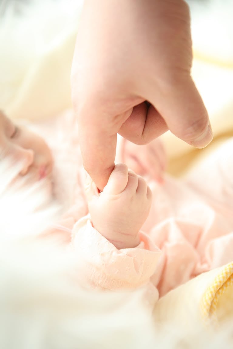 un bébé qui tient la main de sa maman